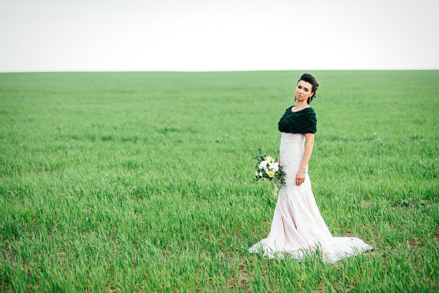 bride with a bouquet in an ivory dress and a knitted shawl photo