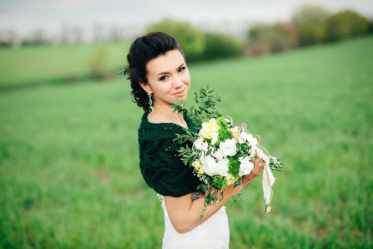 bride with a bouquet in an ivory dress and a knitted shawl photo