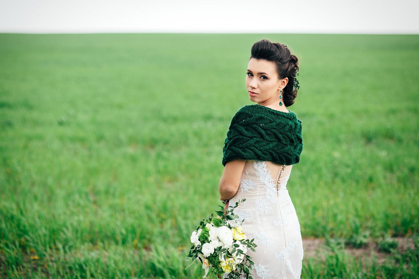 bride with a bouquet in an ivory dress and a knitted shawl photo