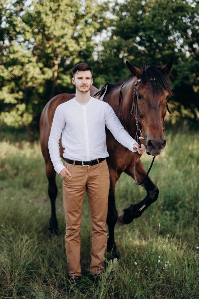 guy in a white shirt on a walk with brown horses photo
