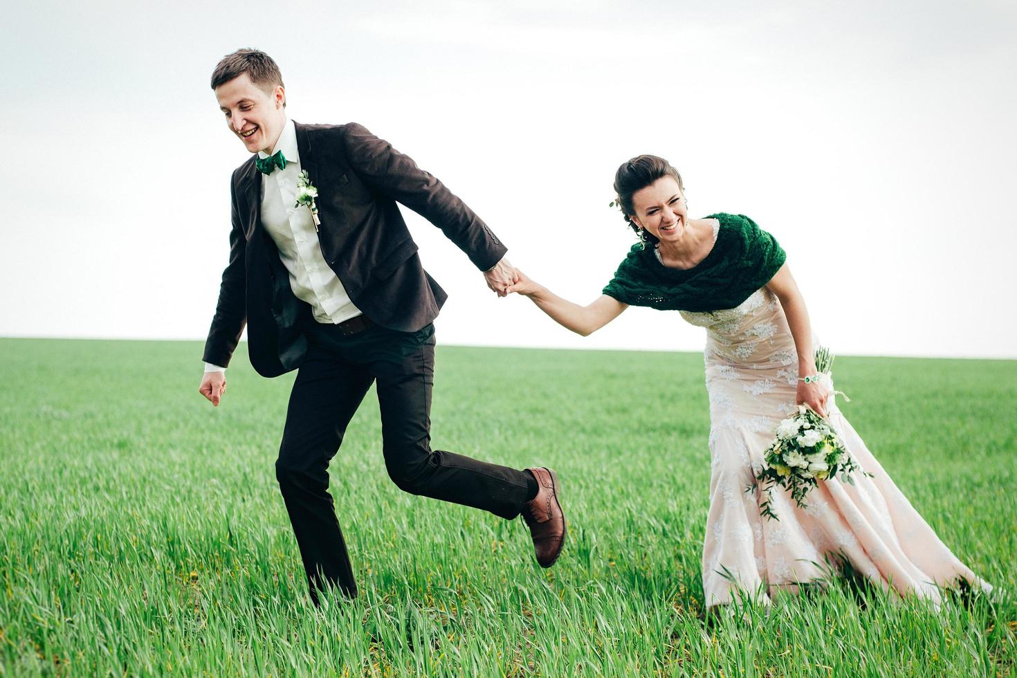 the groom in a brown suit and the bride in an ivory-colored dress on a green field photo