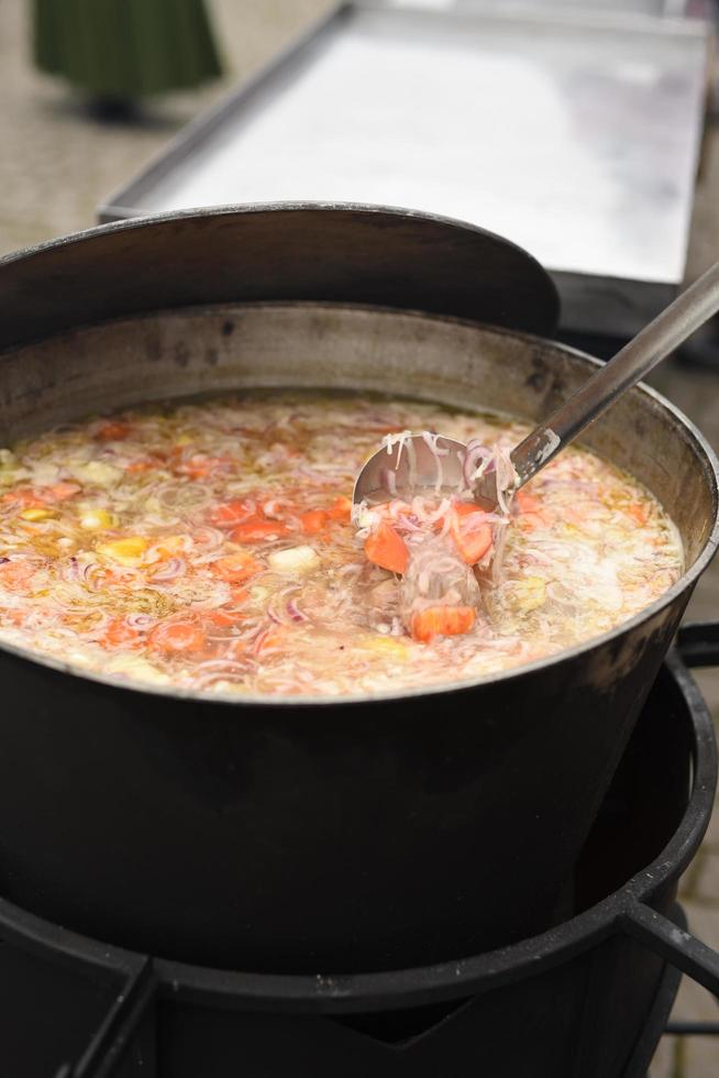 meat soup with herbs and spices boils over the fire photo