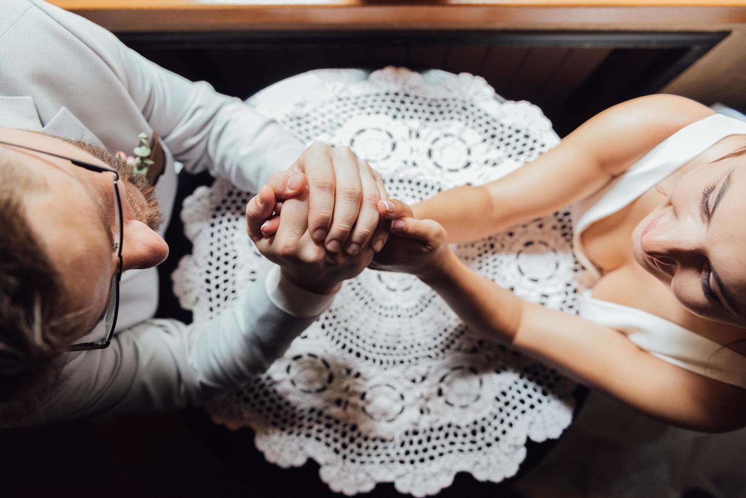 guy in a suit and a girl in a dress are sitting at the table and holding hands photo