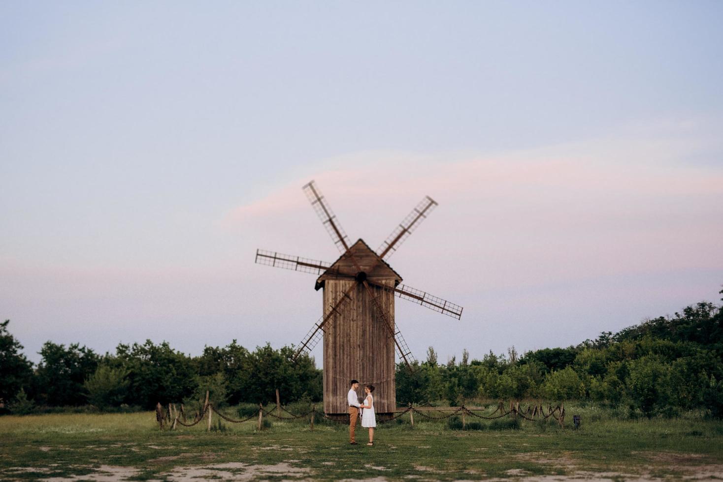 girl in a white sundress and a guy in a white shirt on a walk at sunset with a bouquet photo