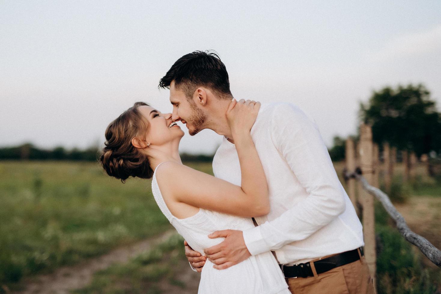 girl in a white sundress and a guy in a white shirt on a walk at sunset with a bouquet photo