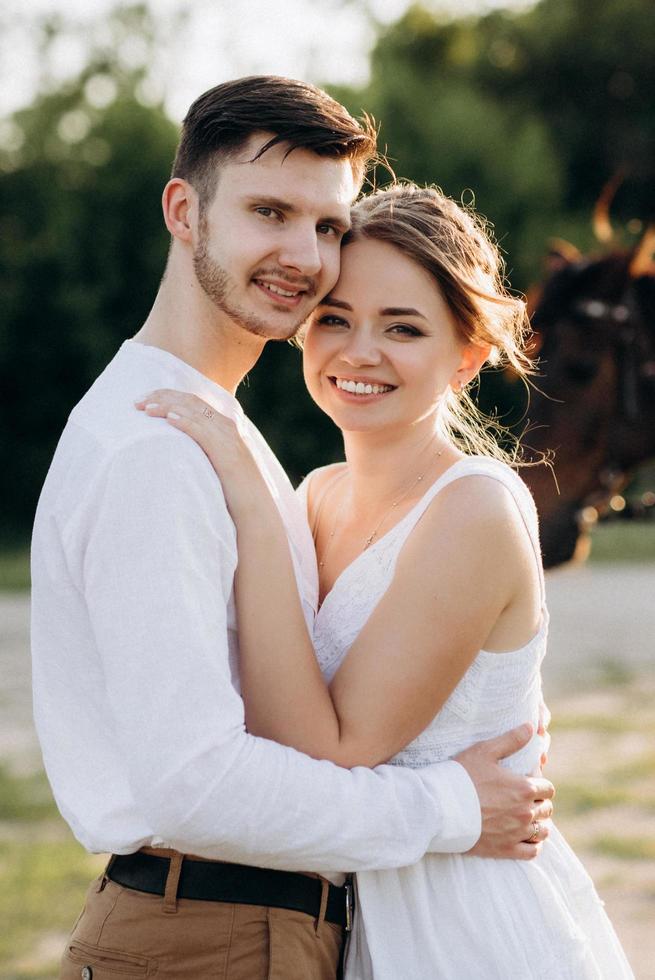 girl in a white sundress and a guy in a white shirt on a walk at sunset with a bouquet photo