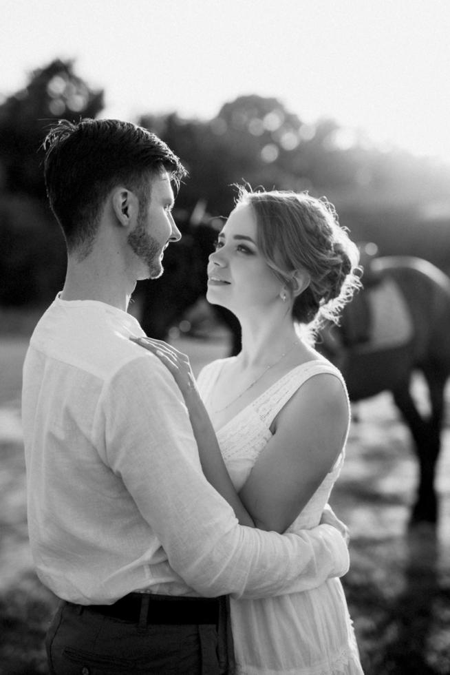 girl in a white sundress and a guy in a white shirt on a walk with brown horses photo