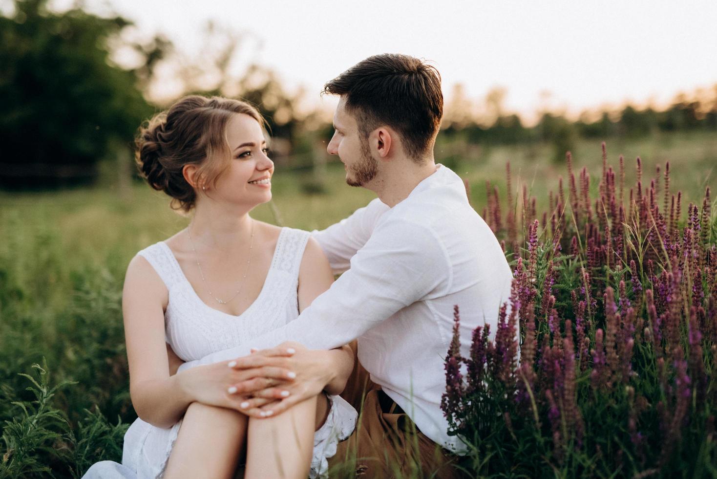 chica con un vestido blanco y un chico con una camisa blanca en un paseo al atardecer con un ramo foto