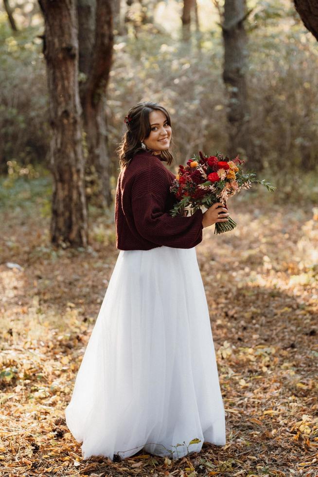 niña en un vestido de novia en el bosque de otoño foto