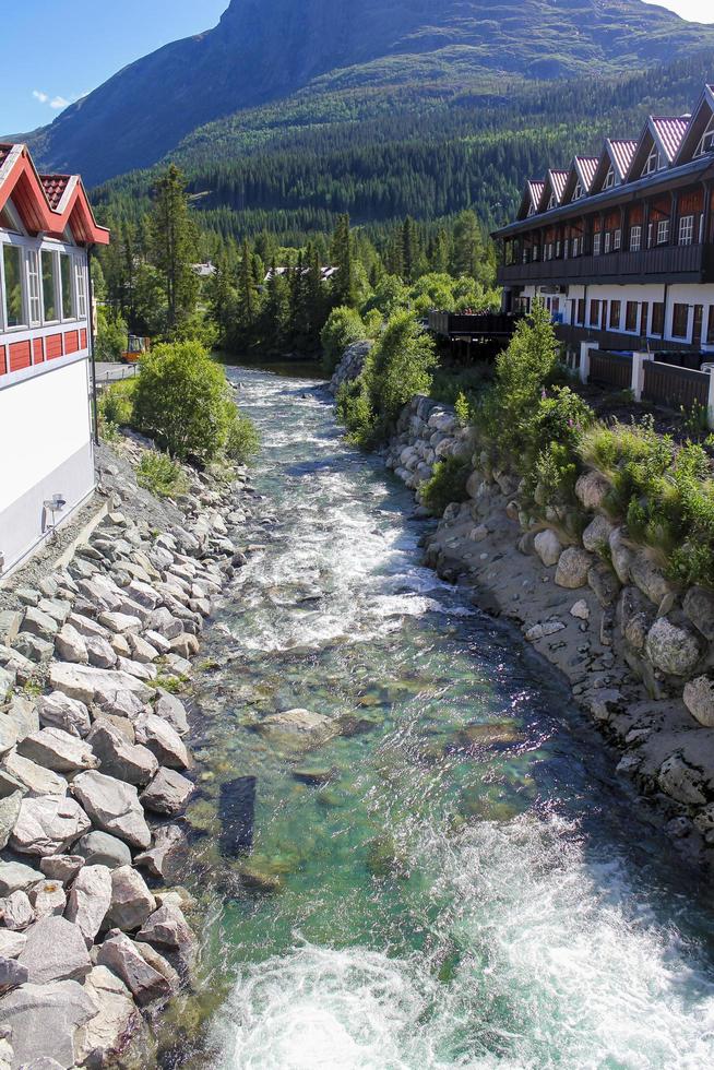 Flowing beautiful turquoise river water between houses in Hemsedal, Norway. photo