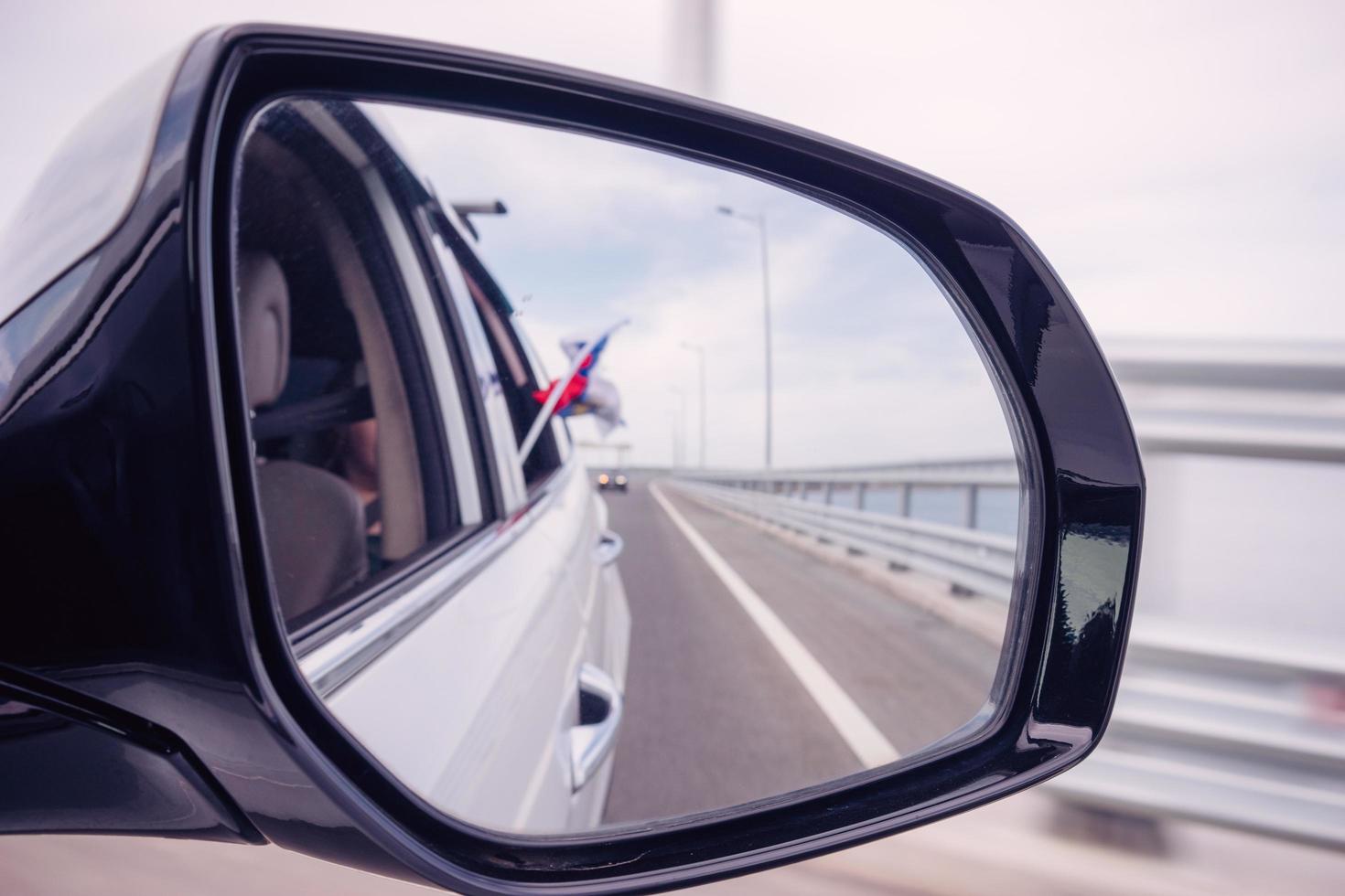 Car mirror with reflection of the road and the Russian flag photo