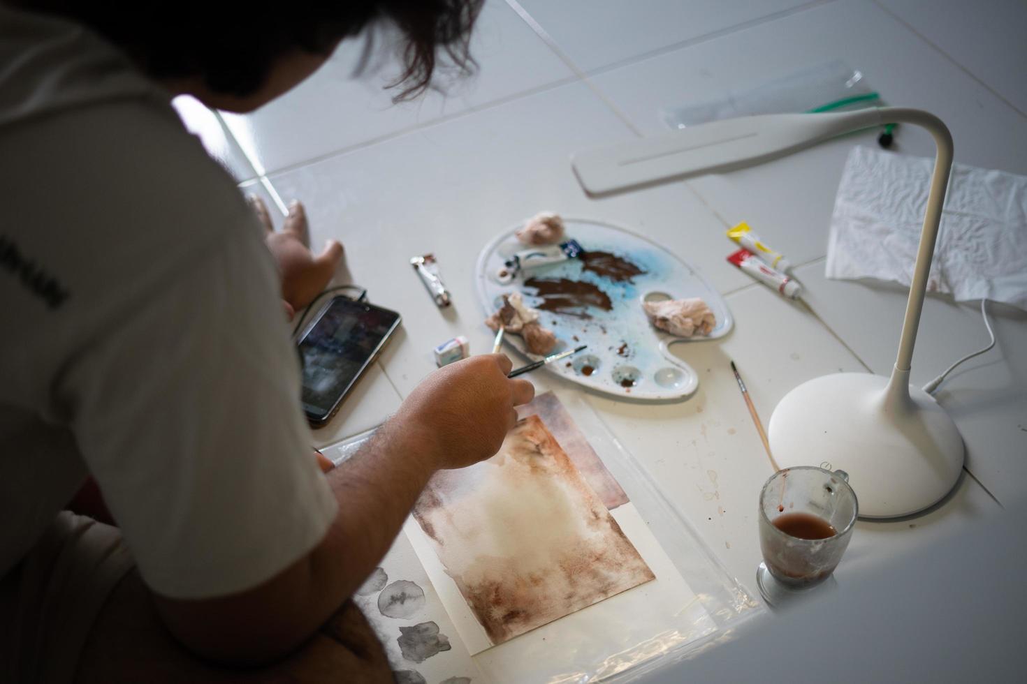 Indonesia 2021. Un hombre está pintando sobre papel con pintura de acuarela. foto