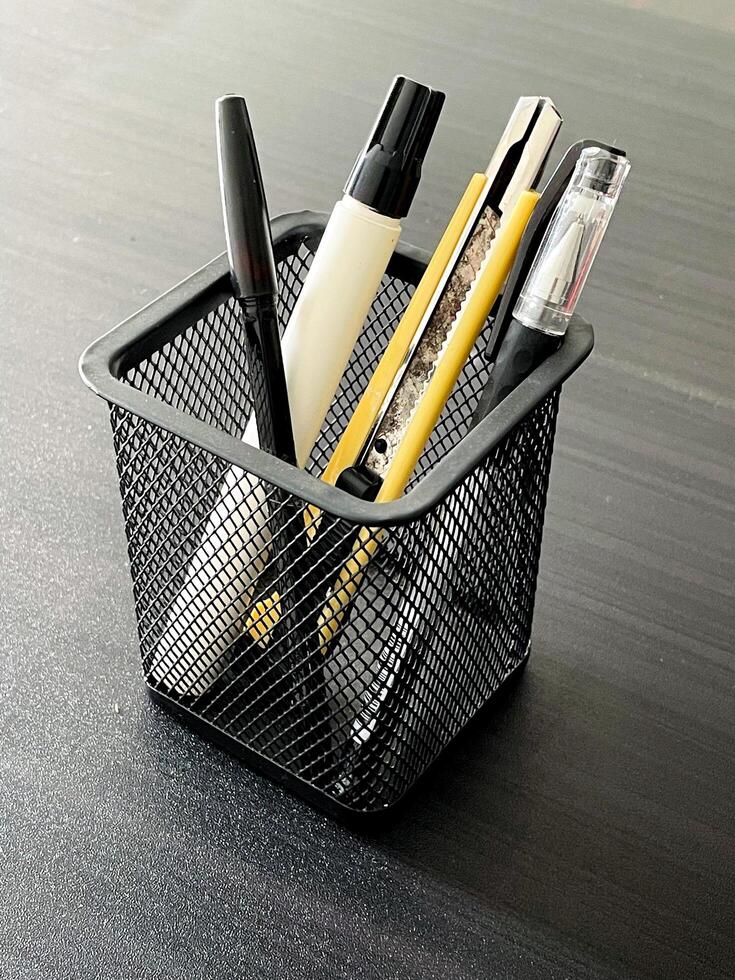 storage box of the stationery. pen, pencil, marker, and cutter in a container. always keep your stuff tidy. photo