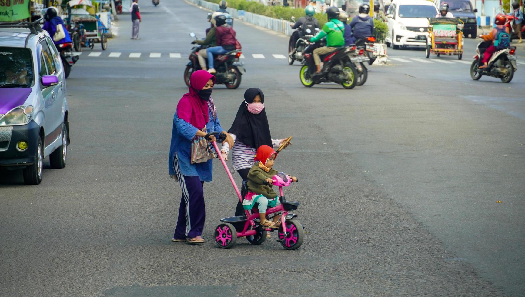 Indonesia 2021. madre con sus hijas cruzando la carretera. foto