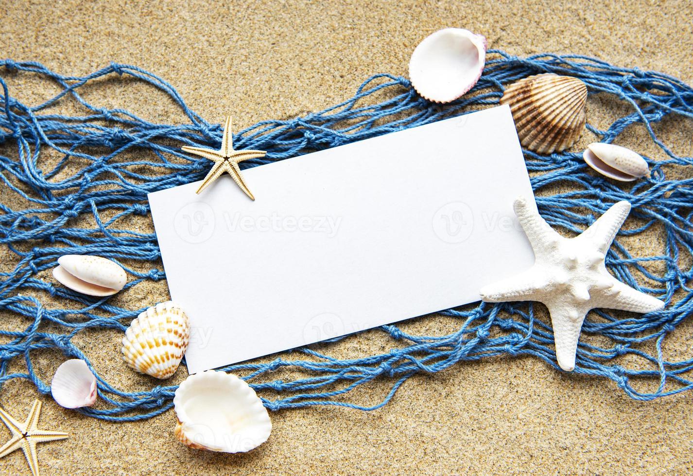 Empty blank of sheet paper on beach sand with sea shells photo