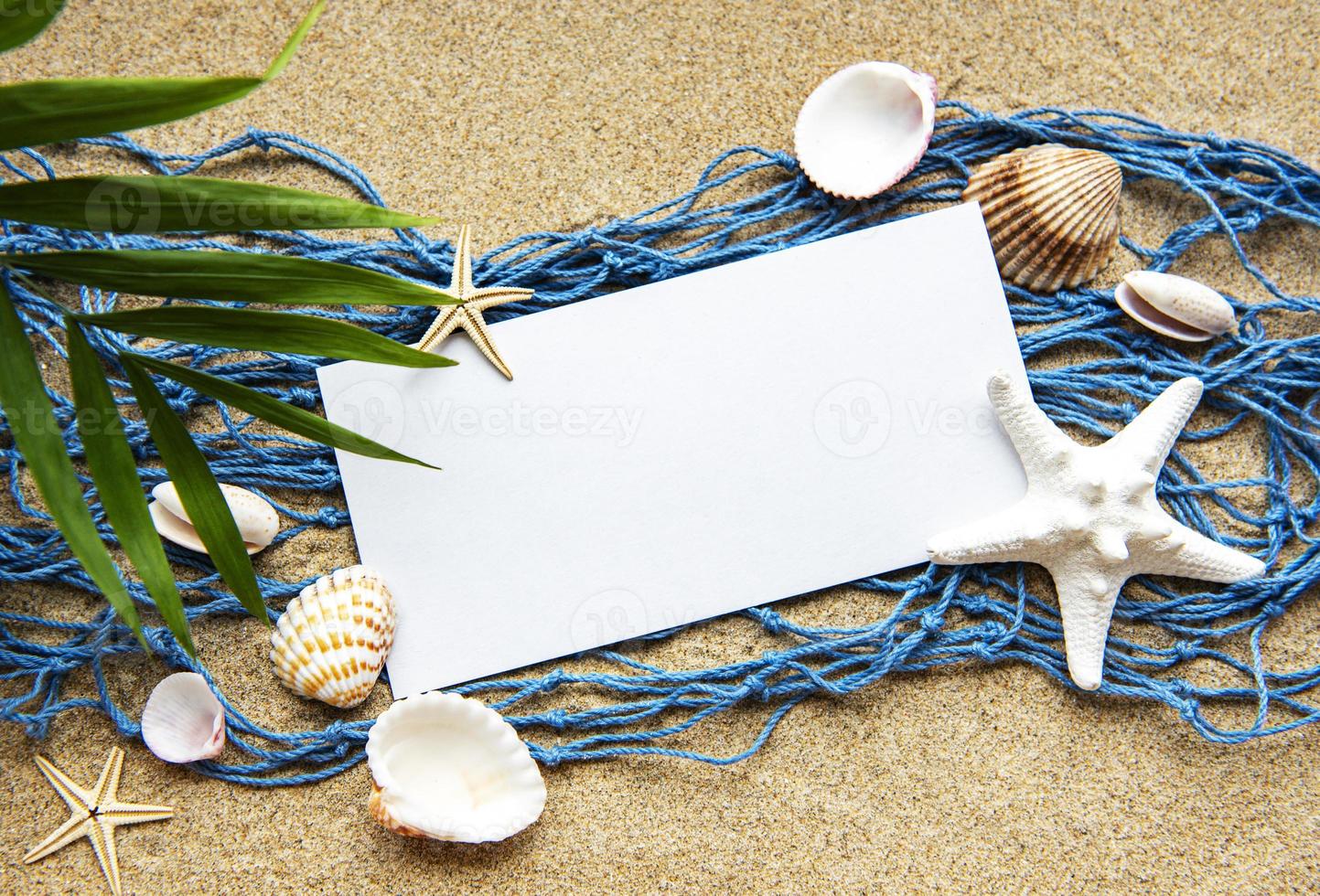 Empty blank of sheet paper on beach sand with sea shells photo