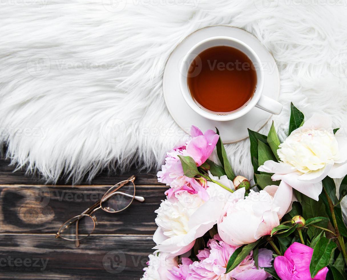 Cup of tea and pink peonies photo