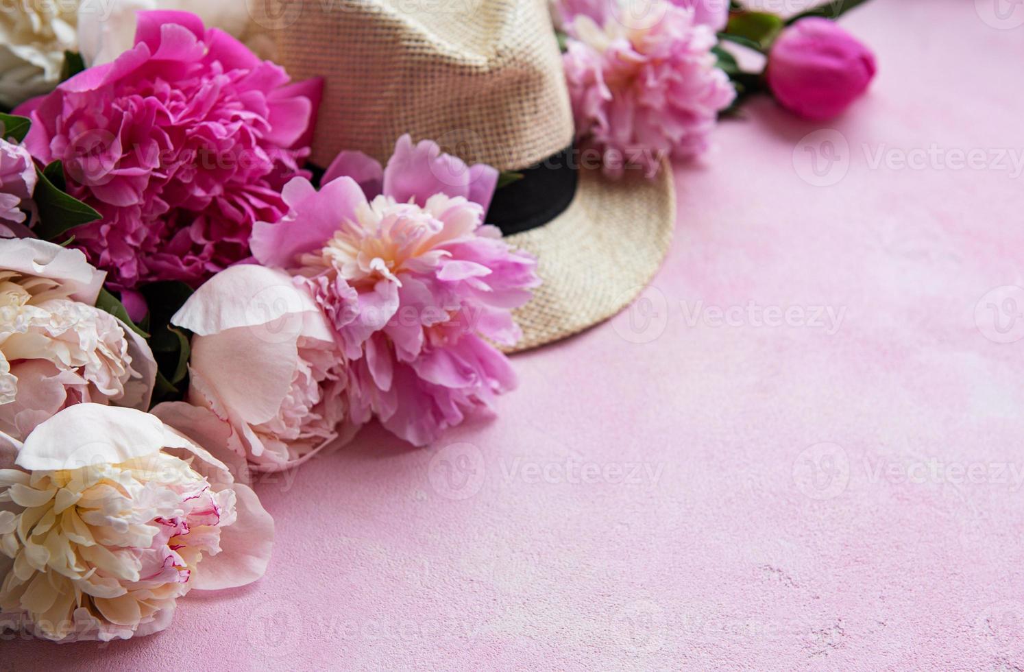 peonías rosas y sombrero sobre un fondo de hormigón rosa foto