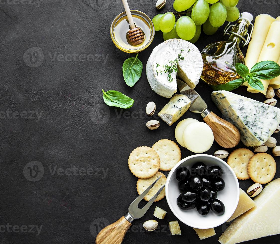 Various types of cheese, grapes, honey and snacks photo