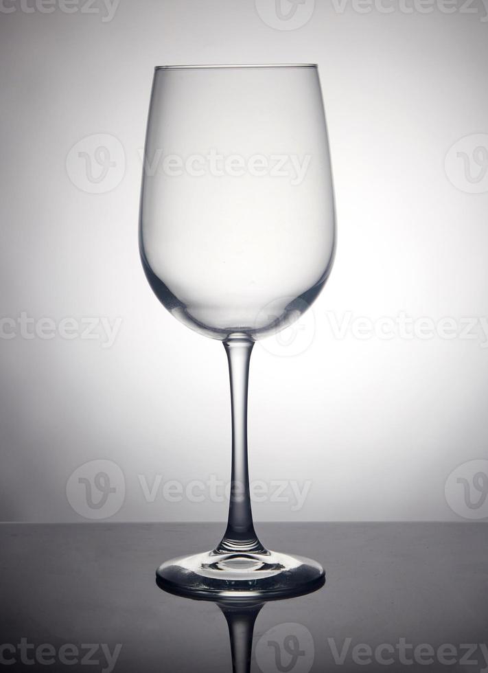 A glass of wine on a gray background, standing on a black stand with reflection photo