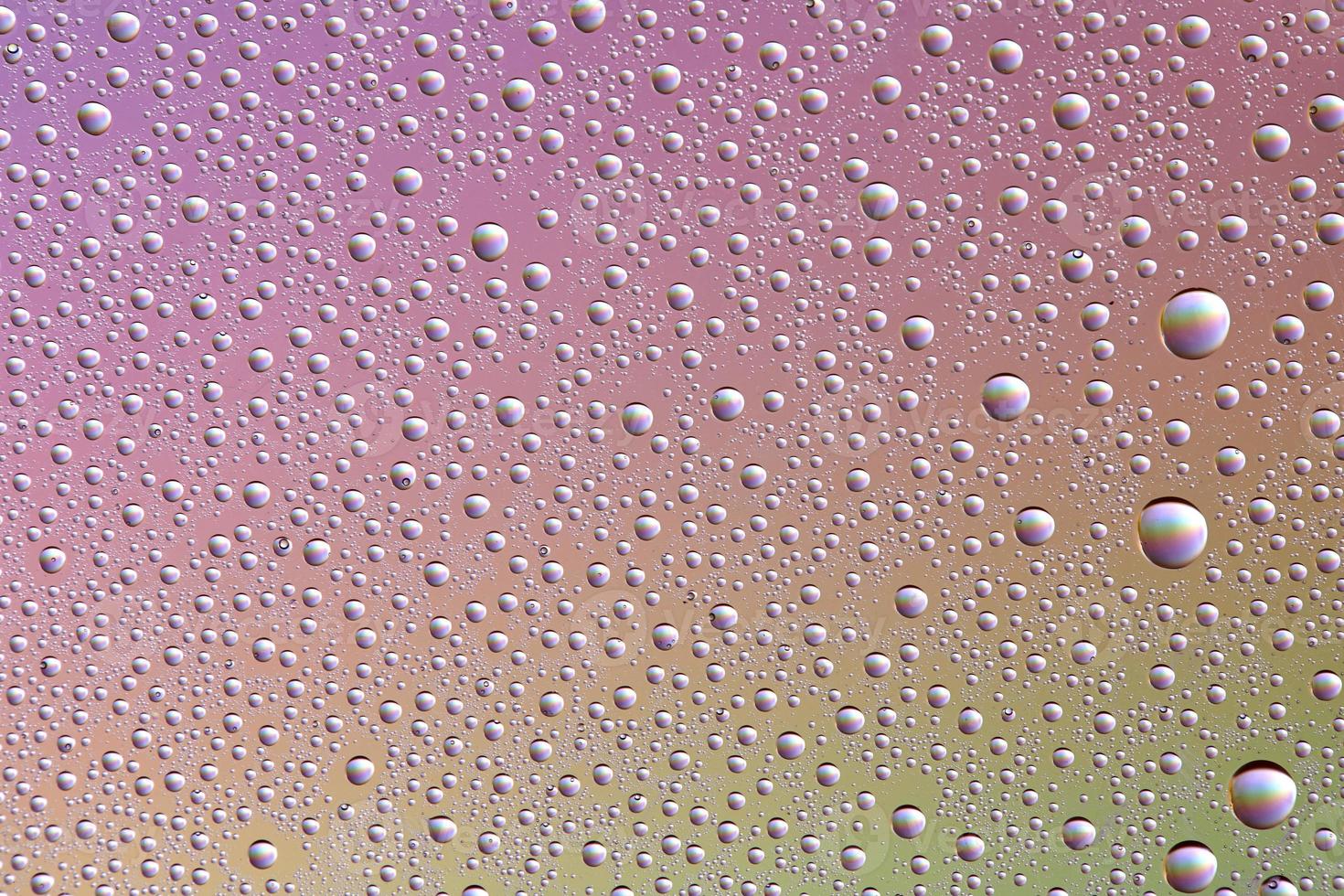 Drops on glass of different sizes and colors on a colored background, texture photo