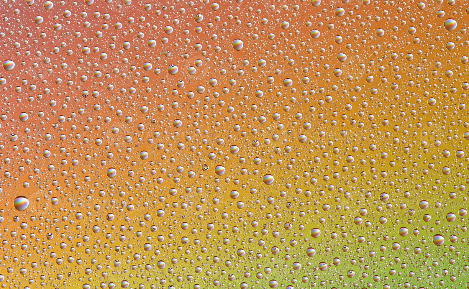 Drops on glass of different sizes and colors on a colored background, texture photo