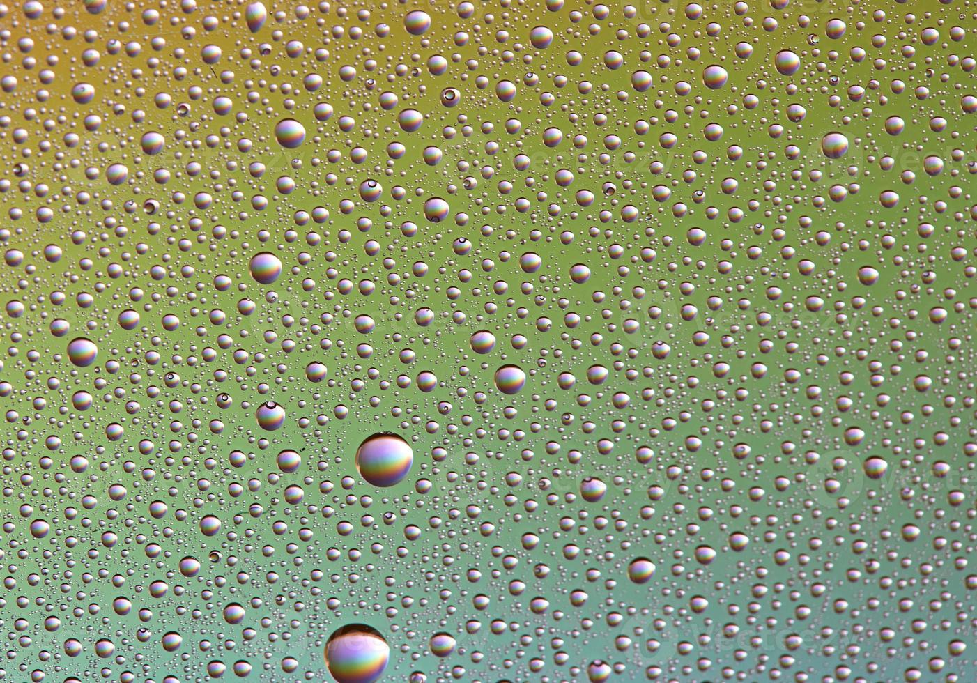 Drops on glass of different sizes and colors on a colored background, texture photo