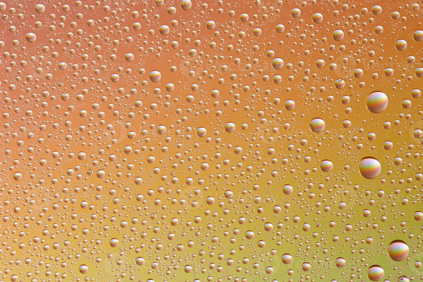 Drops on glass of different sizes and colors on a colored background, texture photo