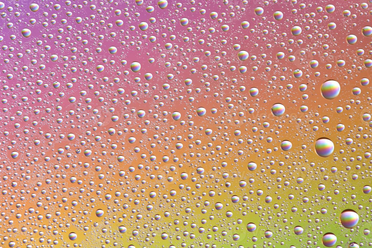 Drops on glass of different sizes and colors on a colored background, texture photo