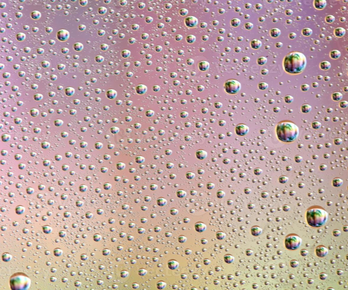 Gotas de vidrio de diferentes tamaños y colores sobre un fondo de color, textura foto