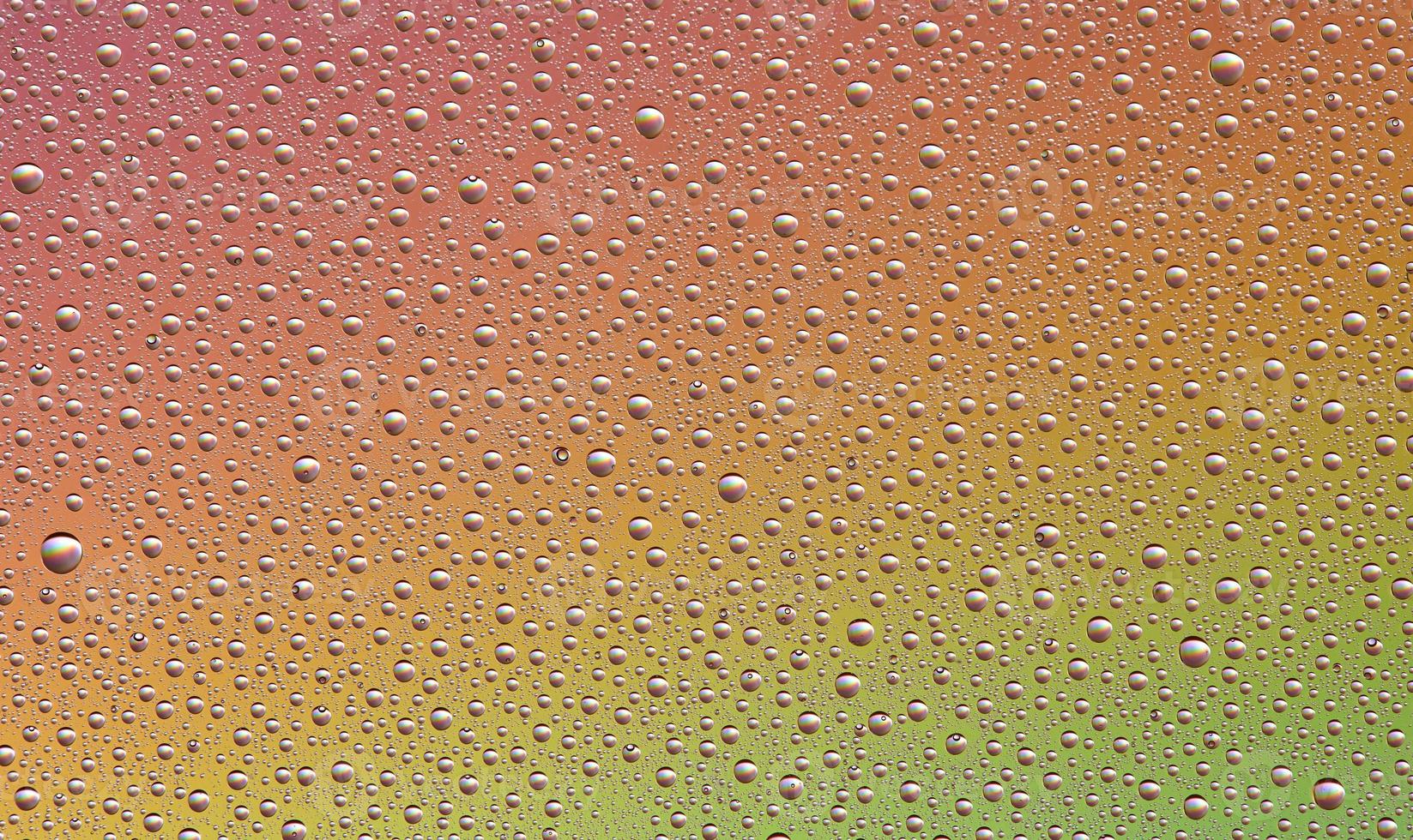 Drops on glass of different sizes and colors on a colored background, texture photo