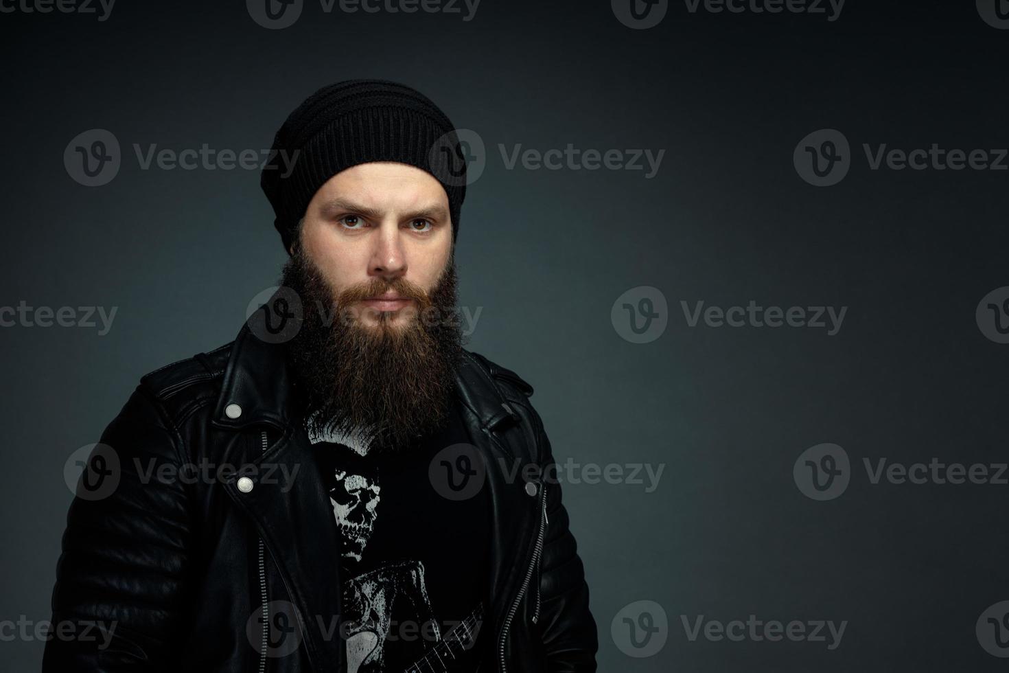 portrait of handsome bearded man in leather jacket and hat looking at the camera photo