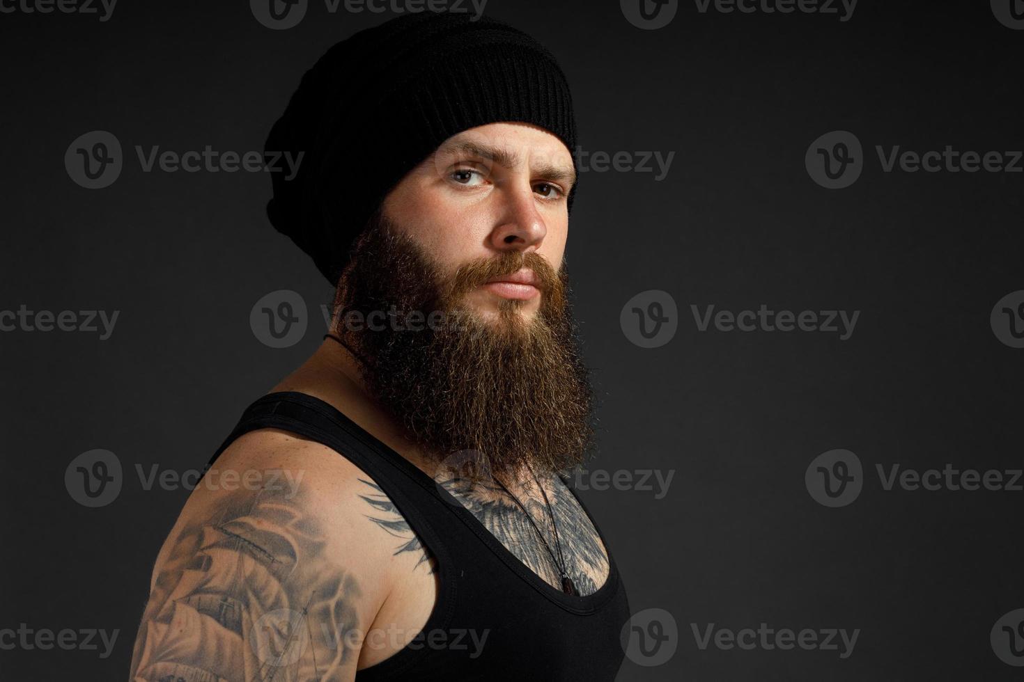 portrait of a handsome bearded man in a black t-shirt and hat looking at the camera photo