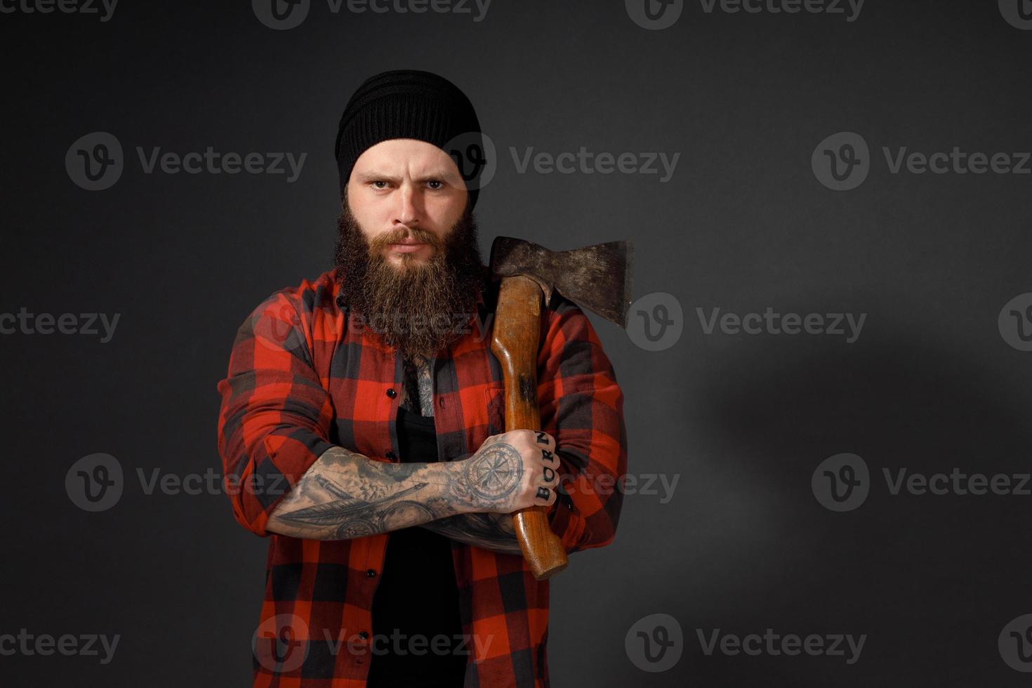 Hombre guapo con cabello largo con un hacha en sus manos sobre un fondo oscuro de estudio foto