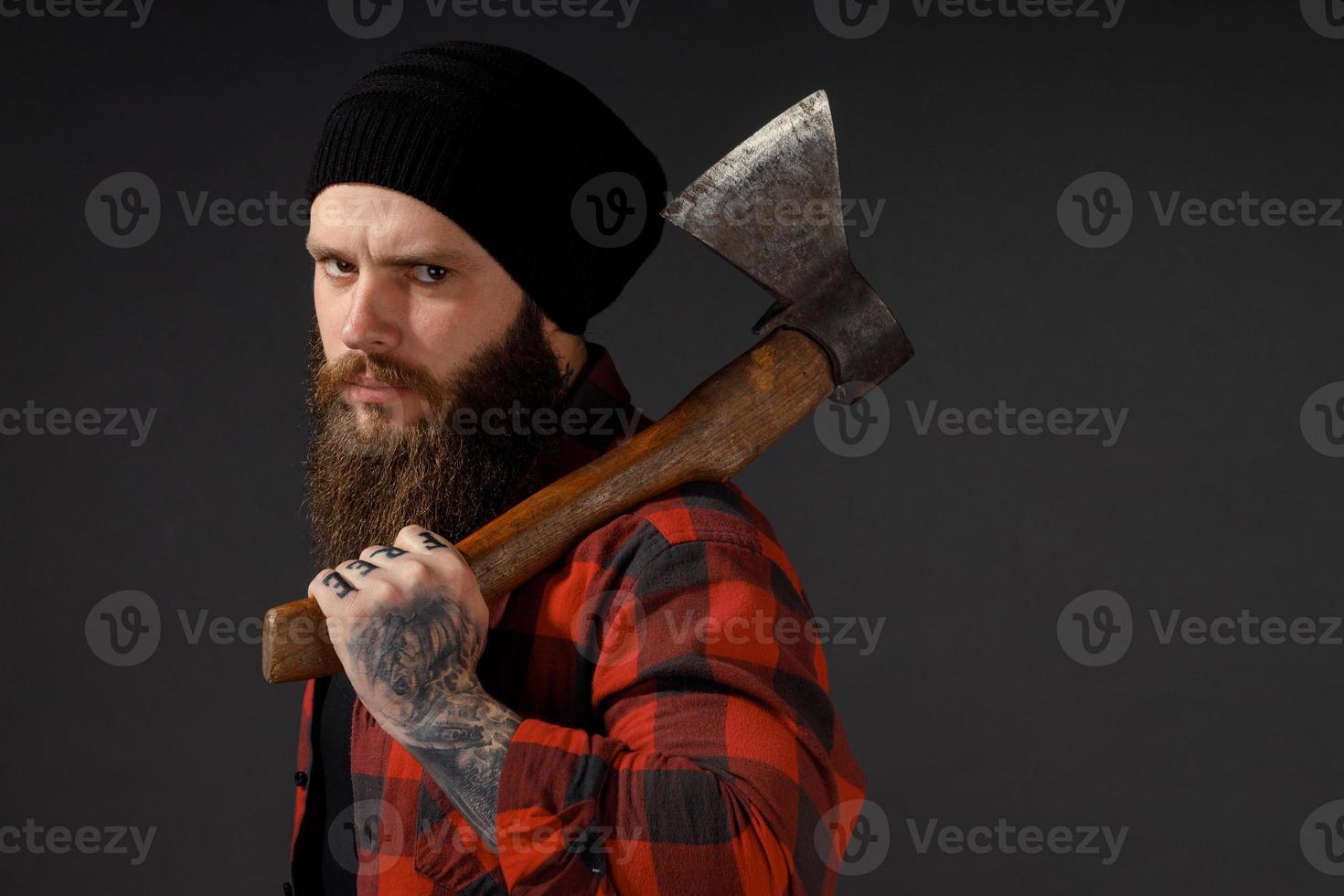 handsome man with long hair with an ax in his hands on a dark studio background photo