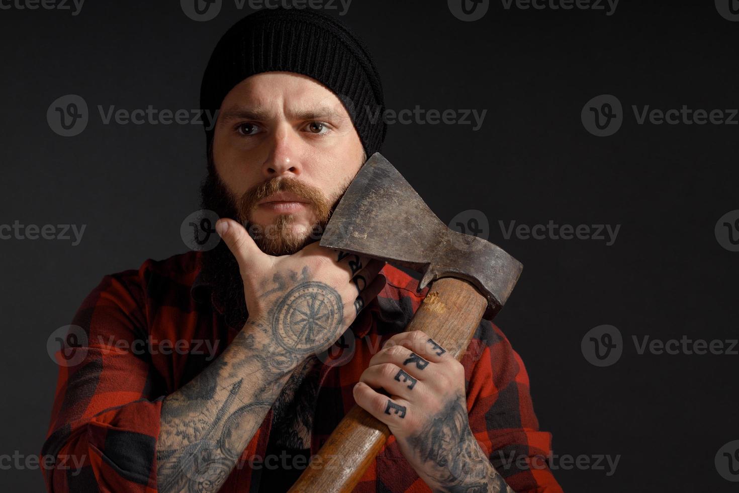 Hombre guapo con cabello largo con un hacha en sus manos sobre un fondo oscuro de estudio foto