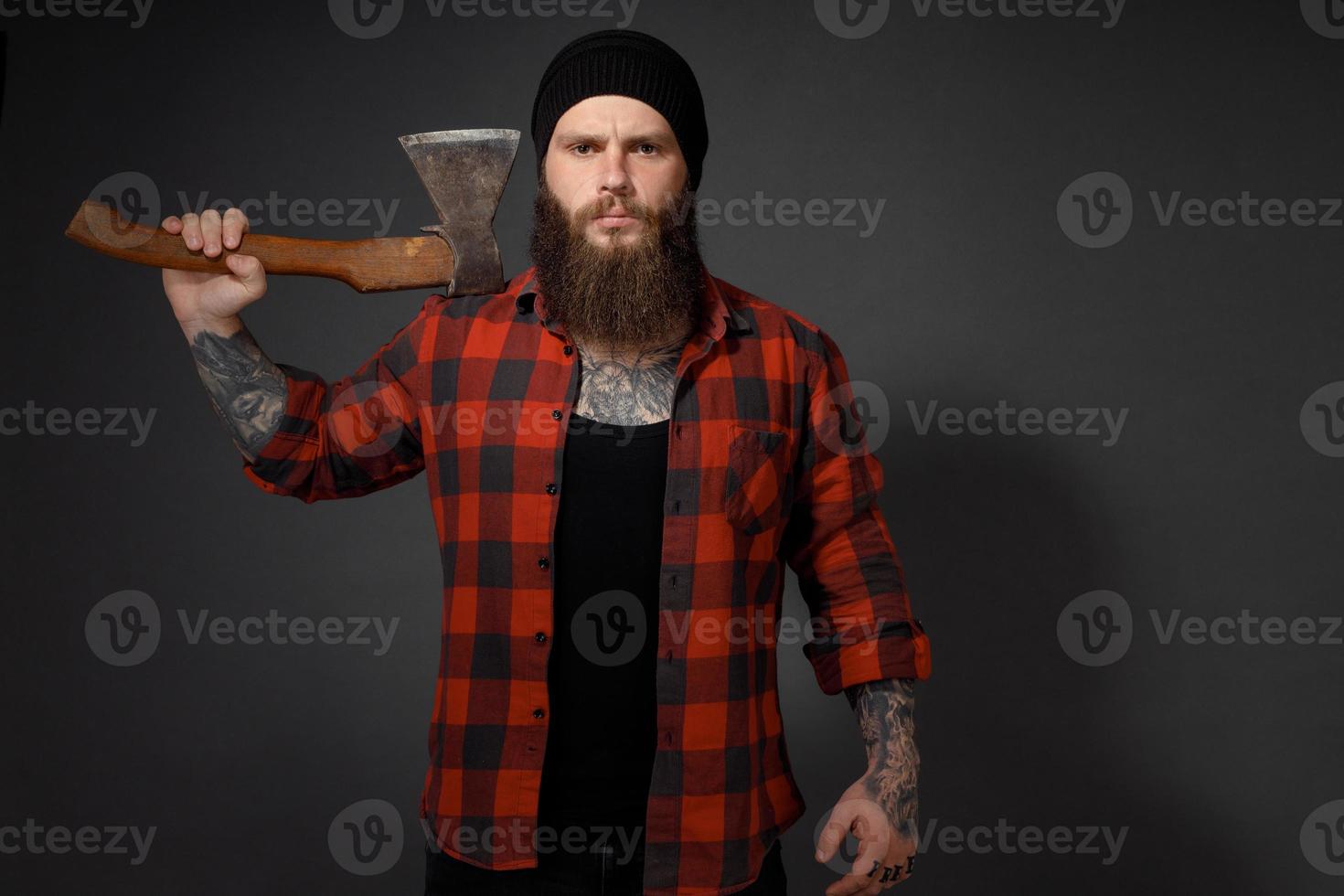 handsome man with long hair with an ax in his hands on a dark studio background photo