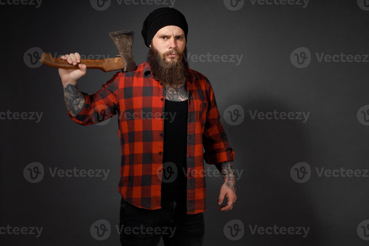 handsome man with long hair with an ax in his hands on a dark studio background photo