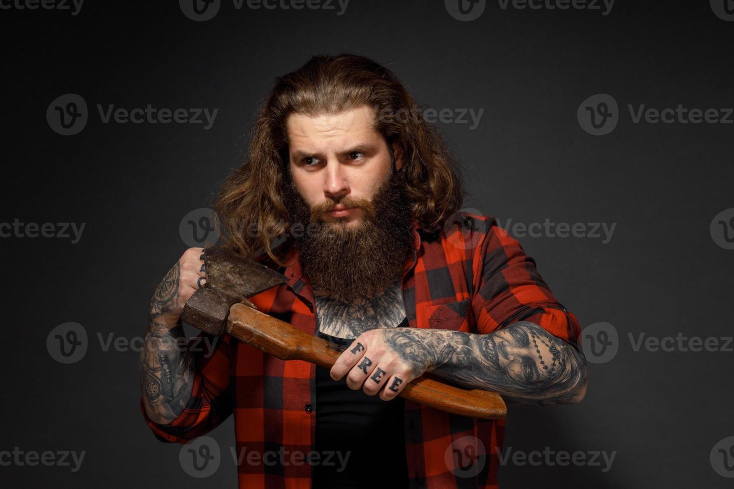 hombre guapo con cabello largo se corta el cabello con un hacha como una barbería foto