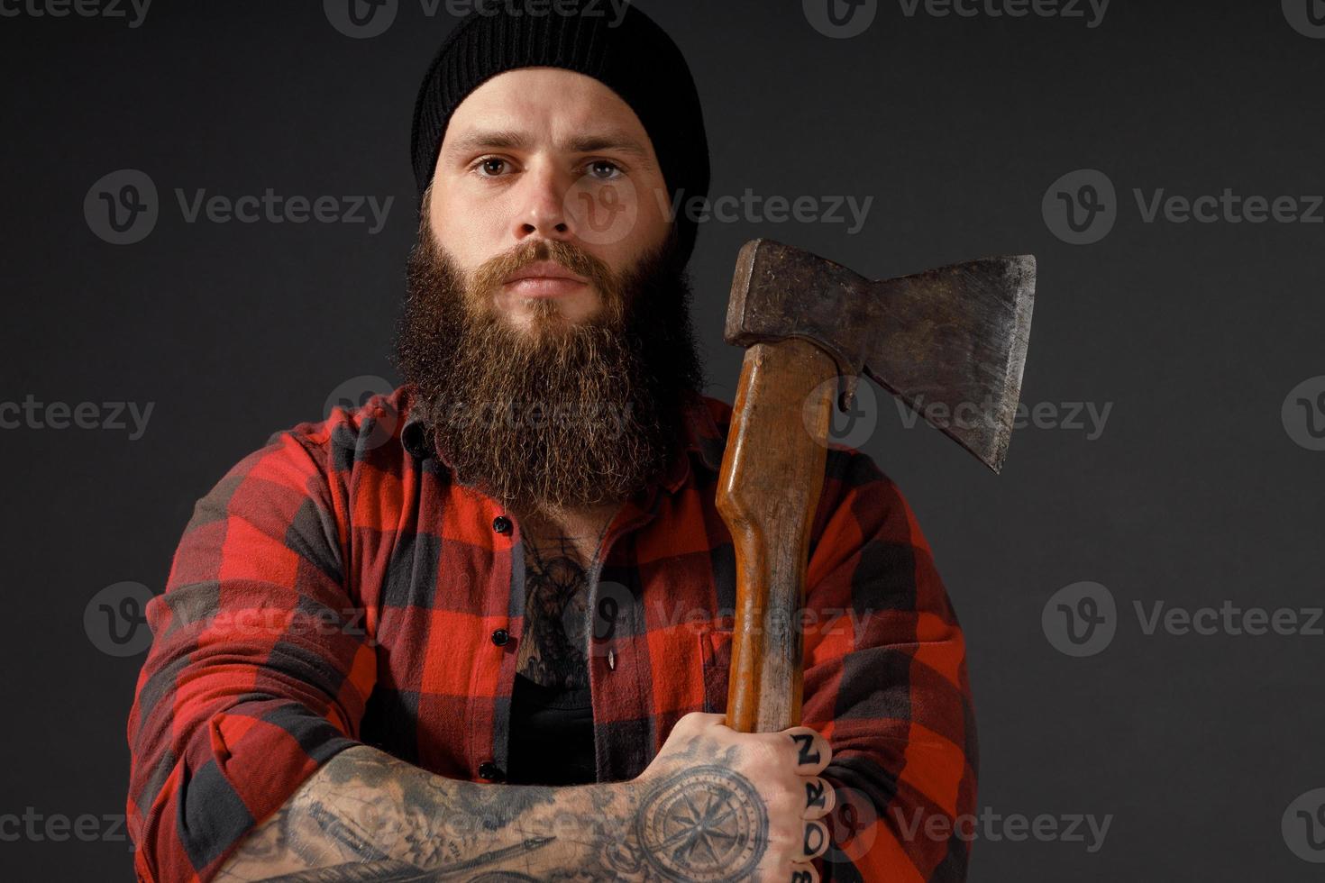 handsome man with long hair with an ax in his hands on a dark studio background photo