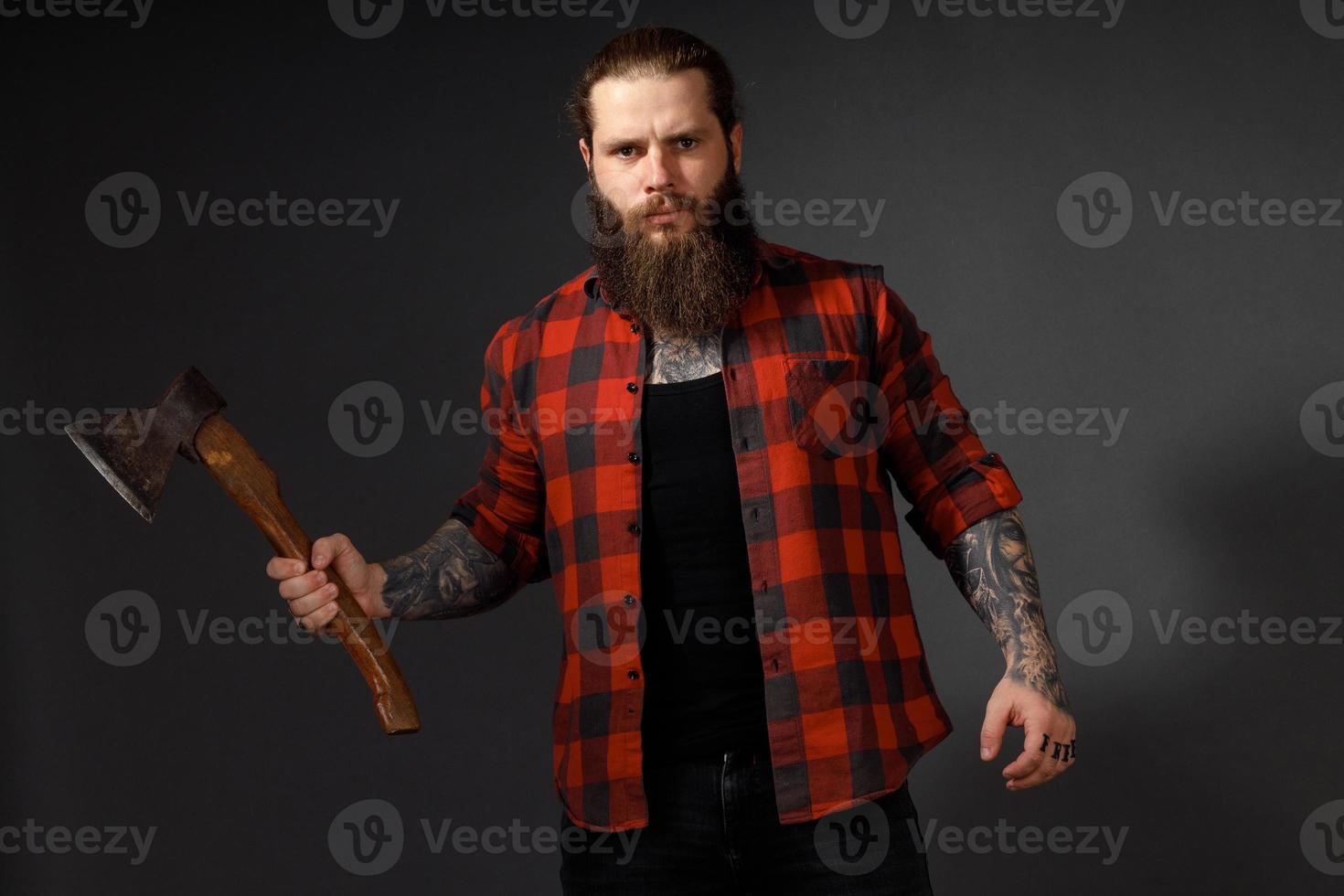 handsome man with long hair with an ax in his hands on a dark studio background photo