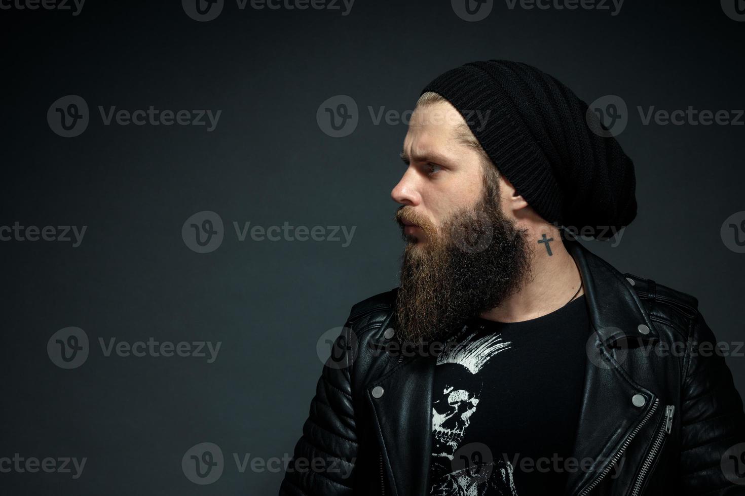 portrait of a handsome bearded man in a leather jacket and hat looking to the side photo