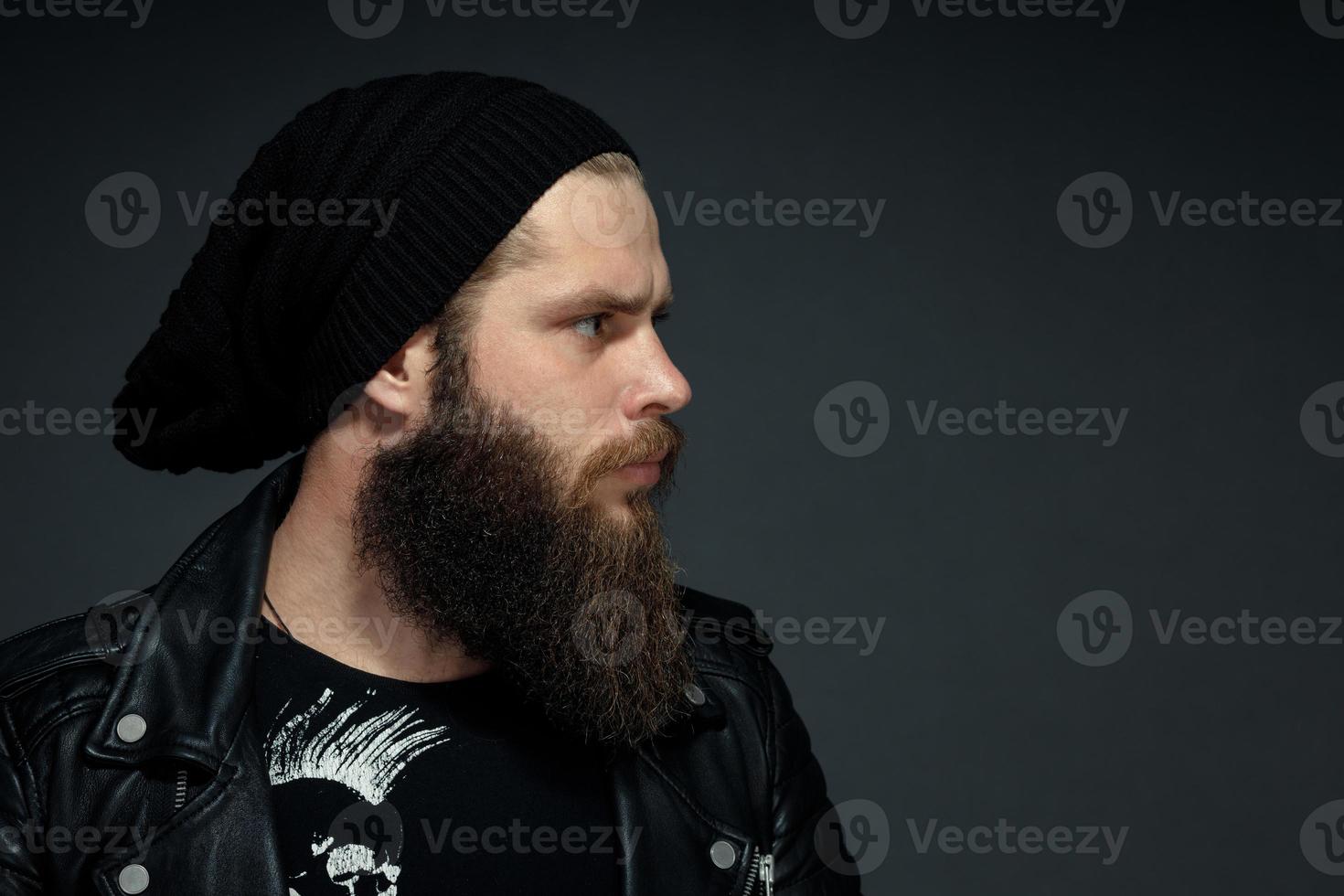 portrait of a handsome bearded man in a leather jacket and hat looking to the side photo