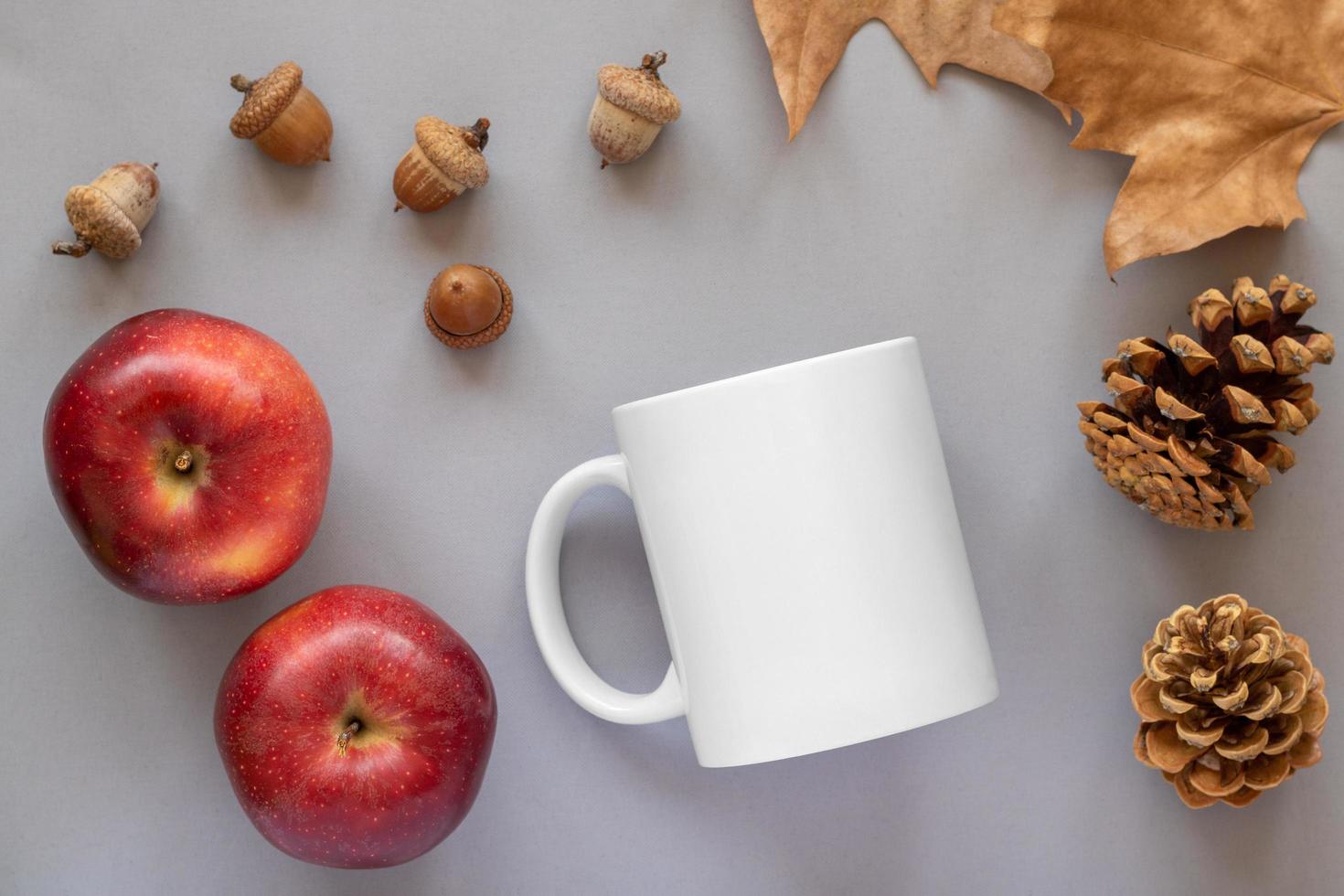 Maqueta de una taza blanca y manzanas sobre fondo blanco. foto