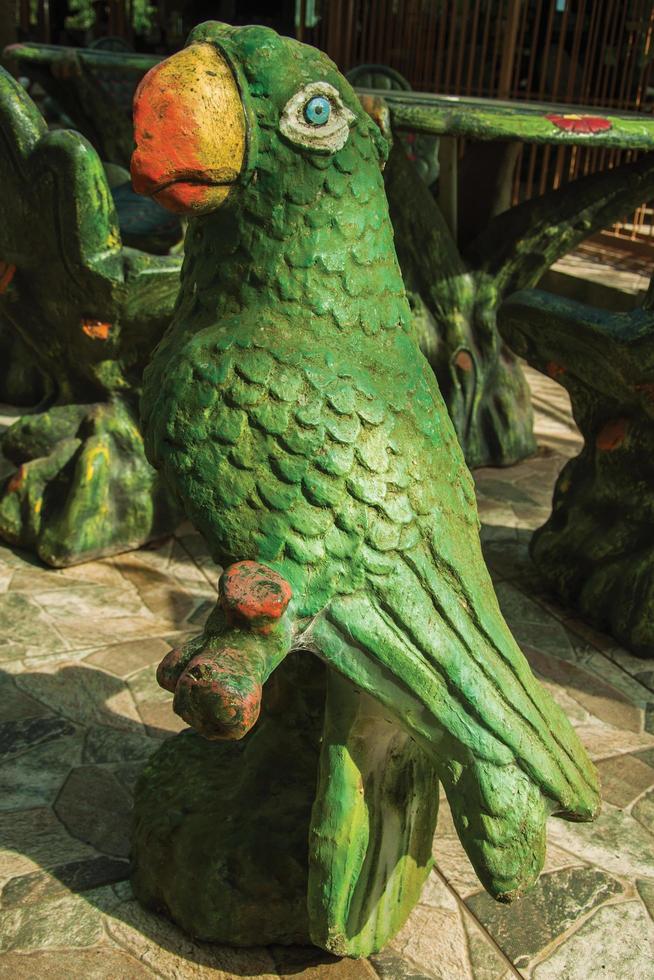 Decorative sculpture of colorful parrot in a rustic furniture ...