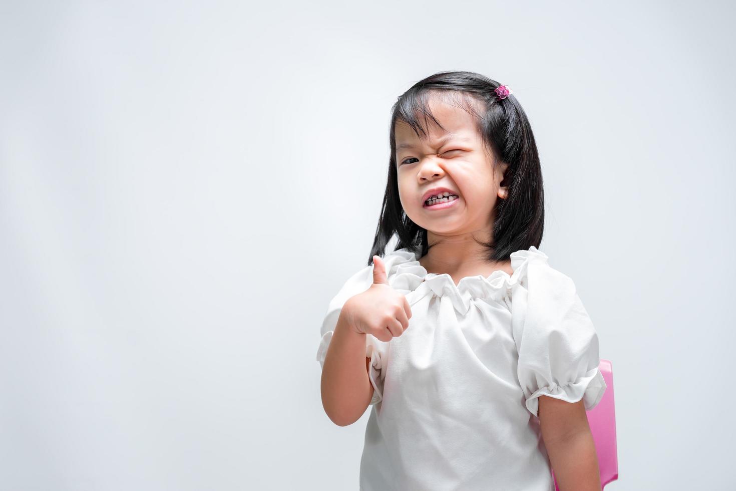 chica asiática pulgar hacia arriba. niño demostró que era genial. los niños sonríen dulcemente. foto