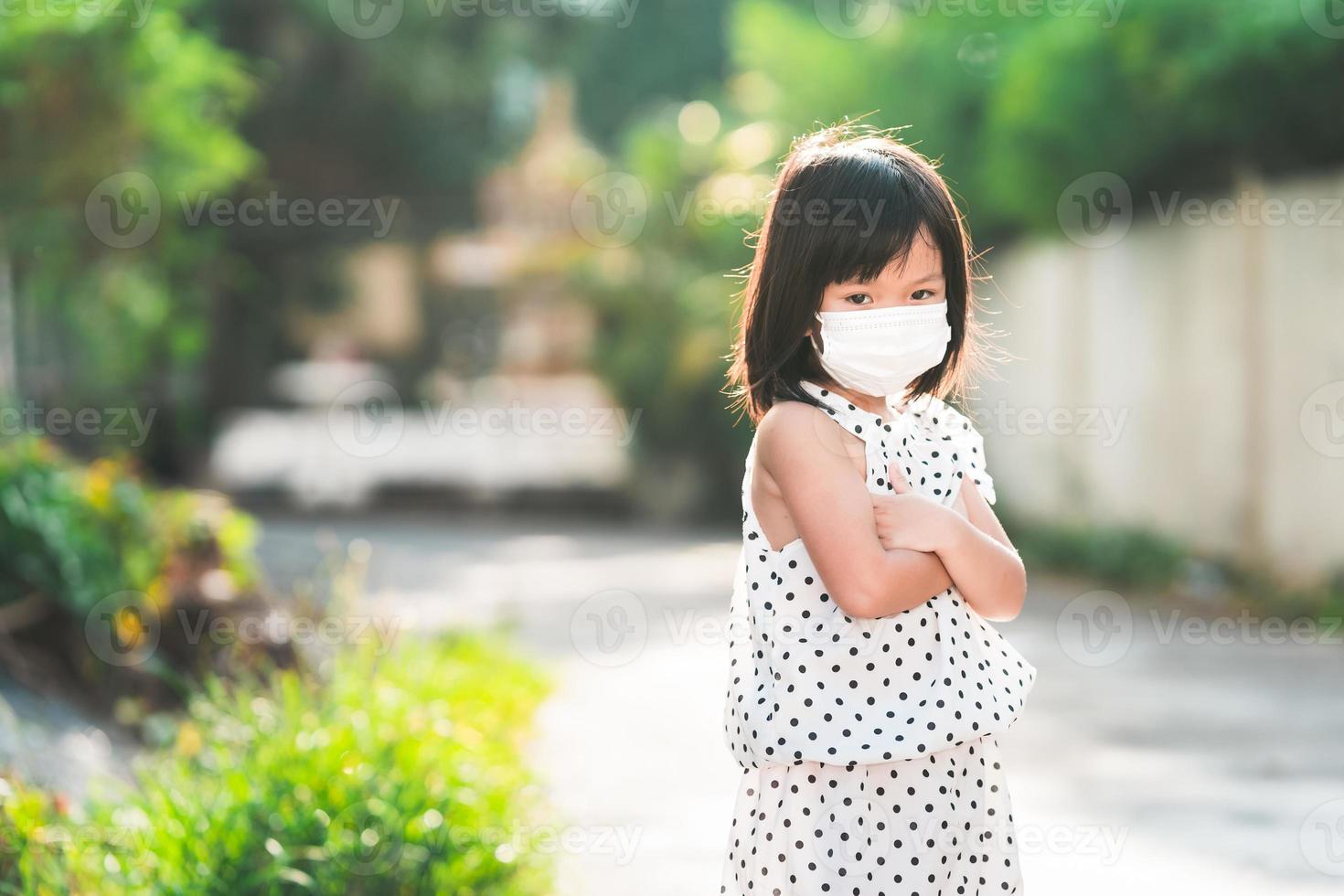 chica con mascarilla médica blanca se encuentra con los brazos cruzados. el niño está molesto. espacio vacío para ingresar texto. foto