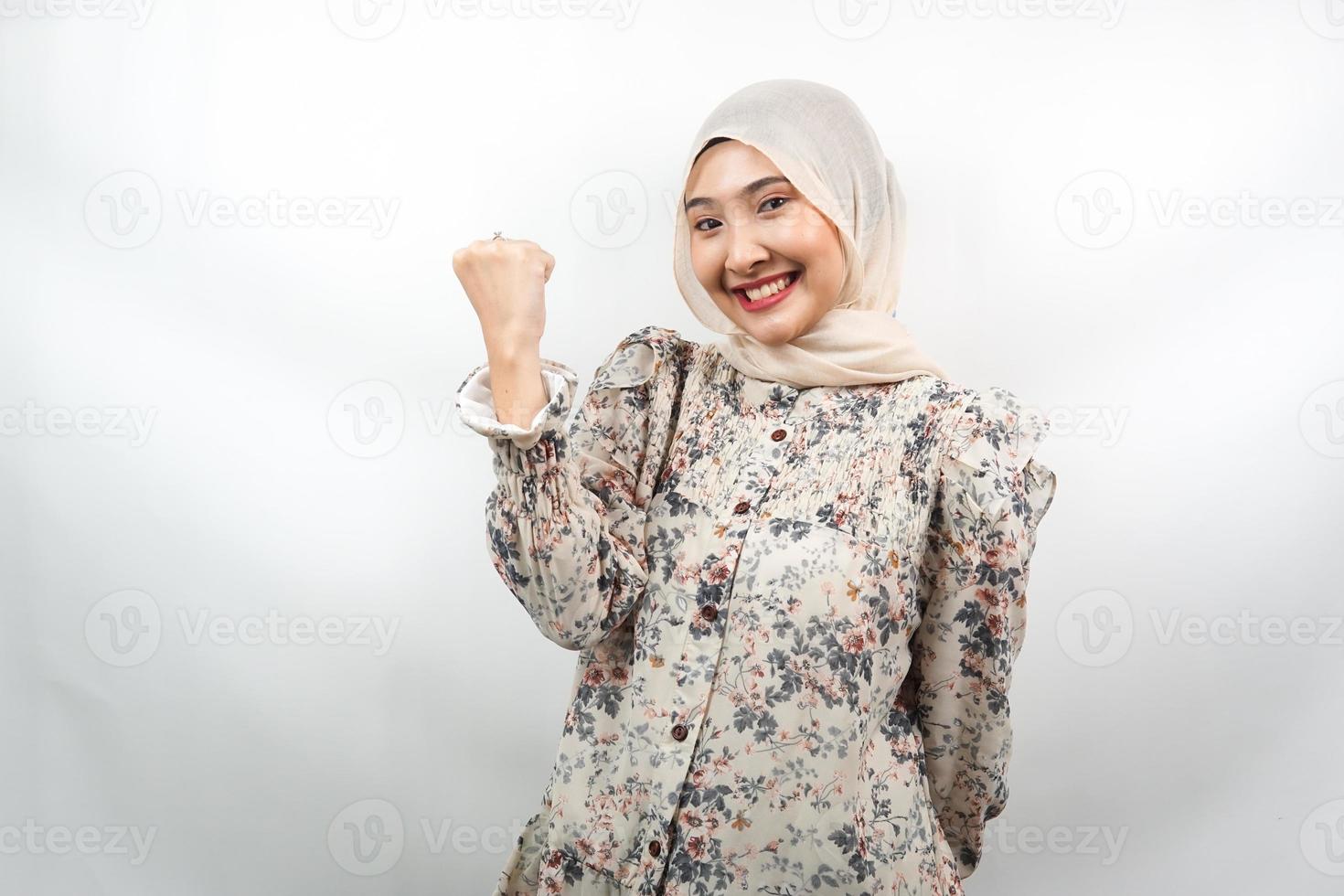 Hermosa joven musulmana asiática sonriendo confiada, entusiasta y alegre con las manos apretadas, signo de éxito, puñetazos, peleas, sin miedo, victoria, aislado sobre fondo blanco. foto