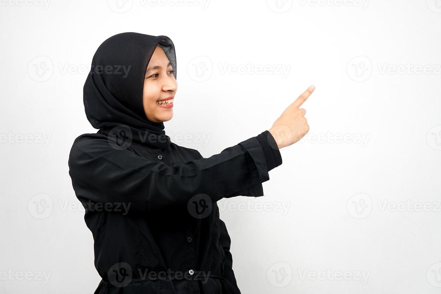 Beautiful asian young muslim woman with hands pointing empty space presenting something, smiling confident, enthusiastic, cheerful, facing empty space, isolated on white background photo
