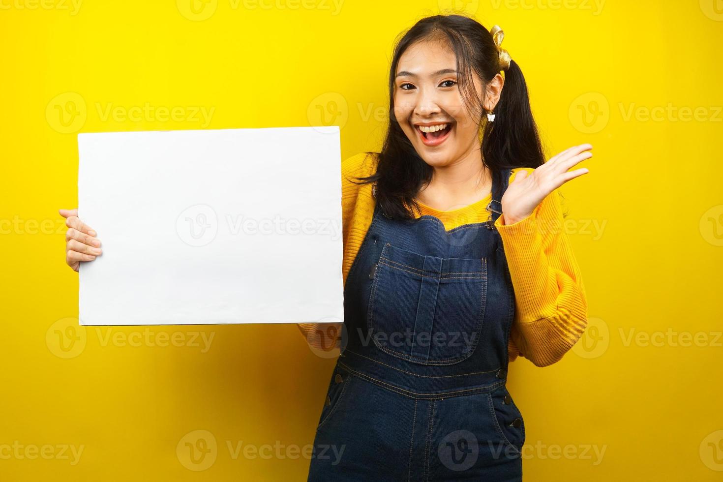 Bonita y linda mujer joven alegre sosteniendo pancarta vacía en blanco, cartel, tablero blanco, tablero de letrero en blanco, tablero de anuncio blanco, presentando algo en el espacio de la copia, promoción foto